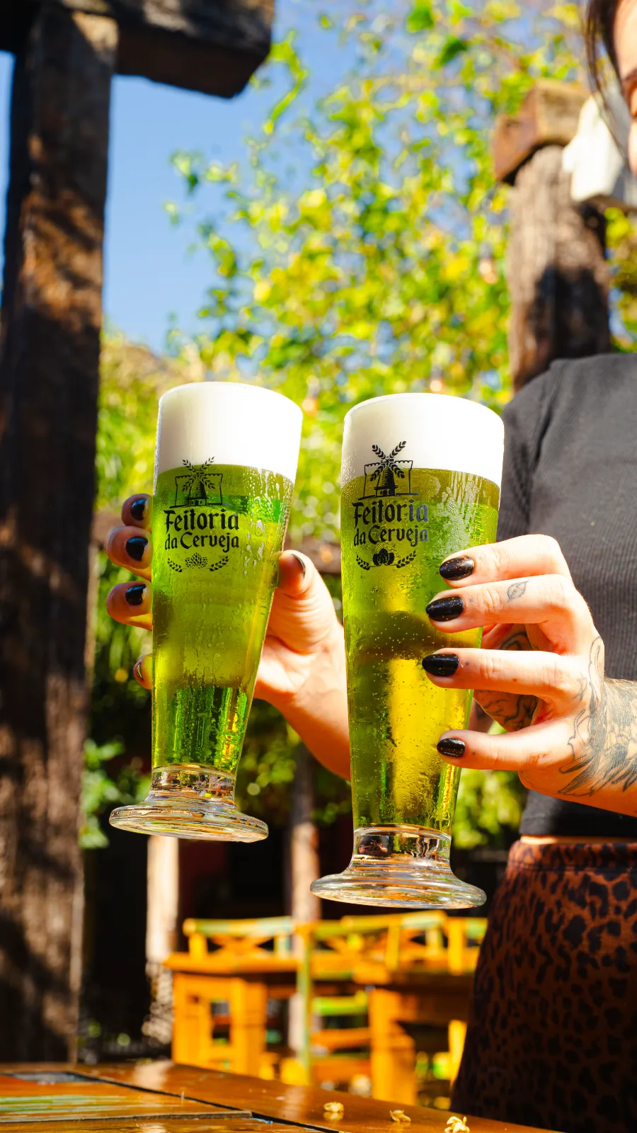 Dois copos de chopp erguidos em brinde no quintal da Feitoria